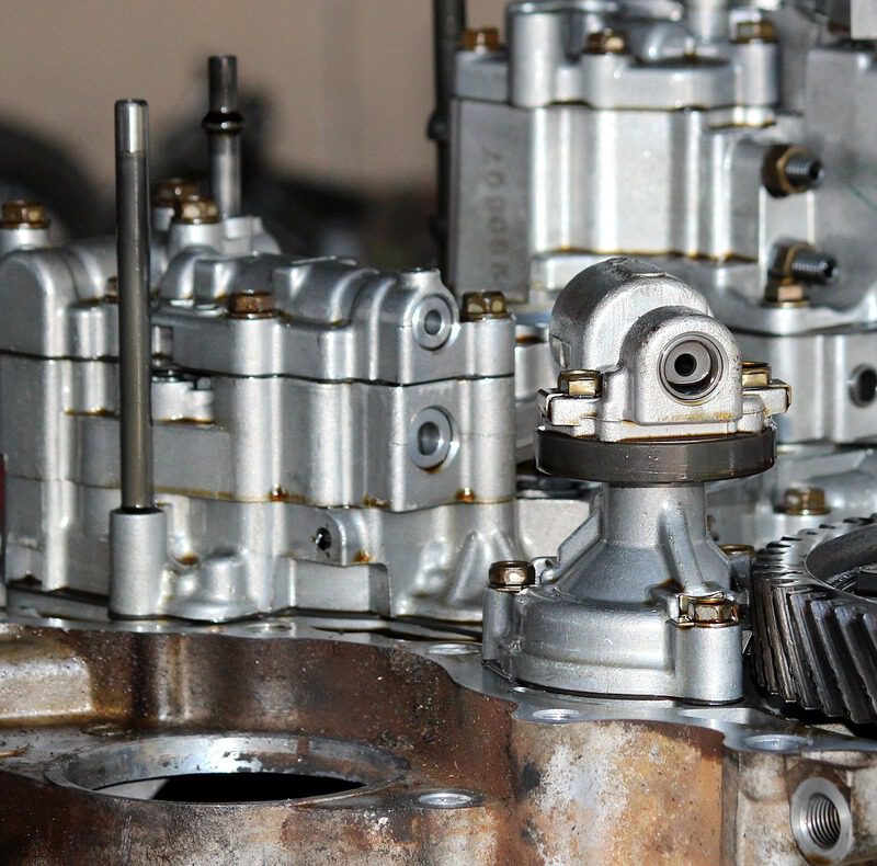 Nahaufnahme eines Motorinnenraums mit metallischen Zahnrädern, die von einem schützenden Ölfilm überzogen sind. Symbolisiert die Schmier- und Schutzfunktion von Motoröl.