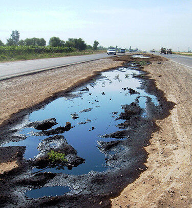 Ausgelaufenes Motoröl auf Asphalt oder Erde. Symbol für die Umweltgefahr durch unsachgemäße Entsorgung von Altöl.