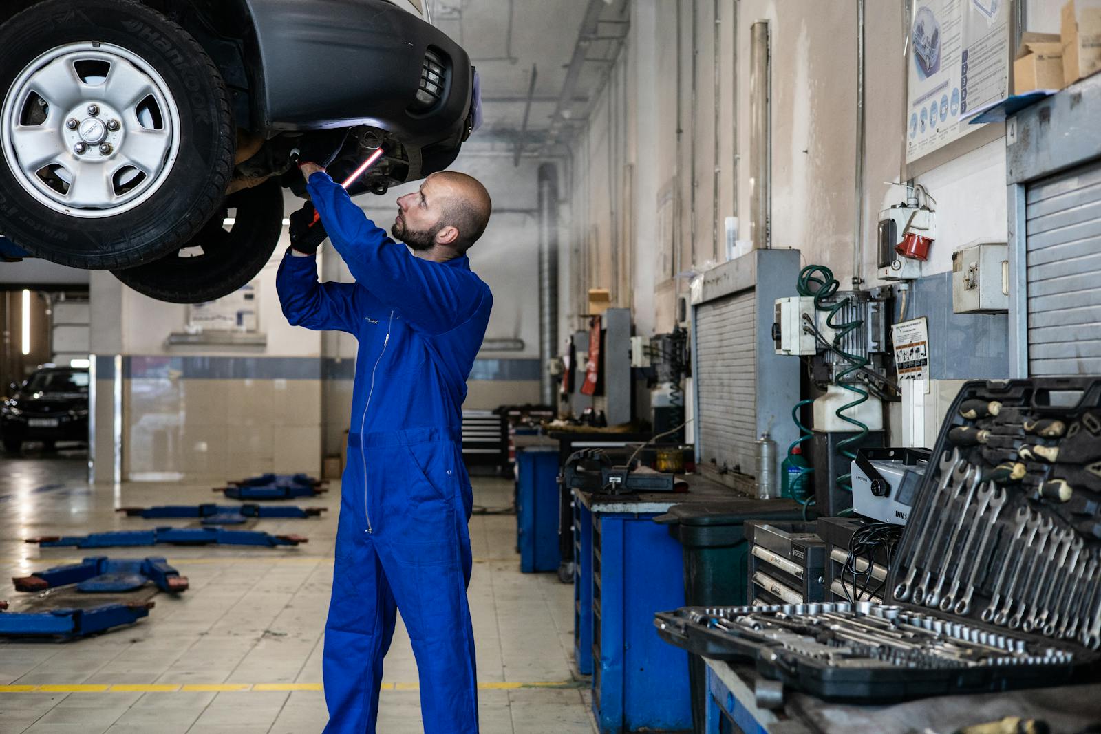 Mechaniker in einer modernen Autowerkstatt prüft den Ölstand und bereitet den Ölwechsel vor. Verdeutlicht die Vorteile des professionellen Services.